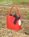 red faux leather bag with black puffy bow charm and coin such that reads "weed money"
