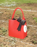 red faux leather bag with black puffy bow charm and coin such that reads "weed money"