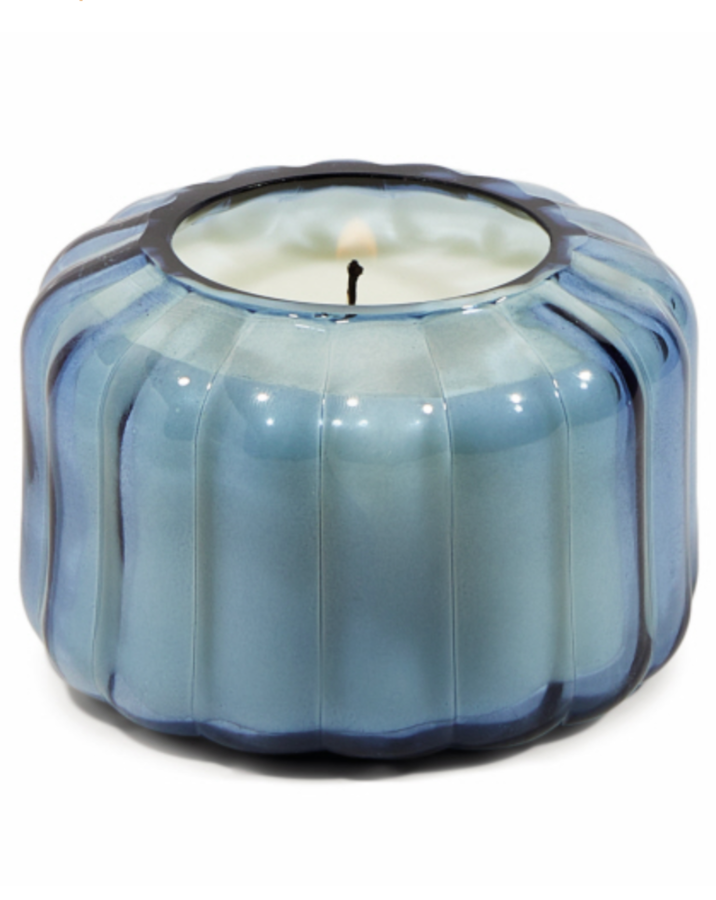 The Ripple - Peppered Indigo 12oz Candle is designed to elevate tablescapes. Bring a vintage touch to your next dinner party with the subtle and finely ribbed colored glass vessels.  Top Notes: Peppered Woods  Middle Notes: Fern Leaf, Spiced Citrus  Base Notes: Oriental Musk
